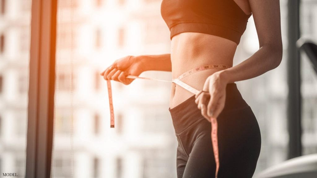 Woman standing with measuring tape around waist (model)