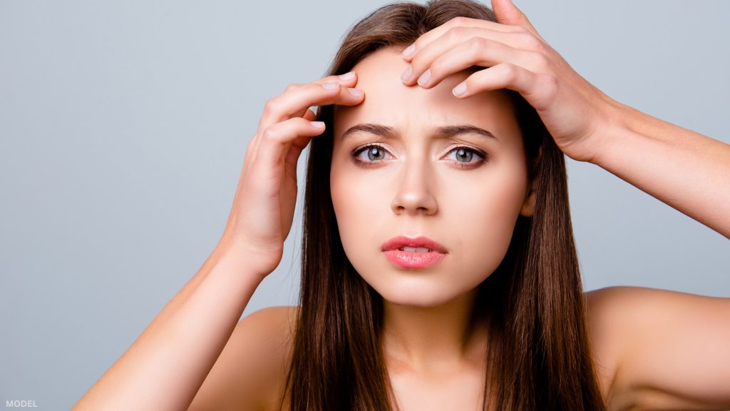 Woman touching forehead squinting eyes (model)