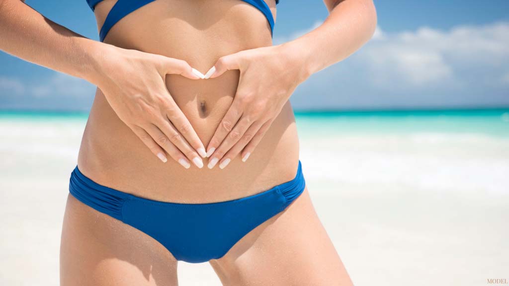 woman in blue bathing suit holding her tummy